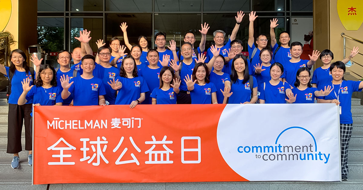 Group of people holding Michelman Commitment to Community banner, volunteering at Hands On.